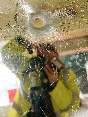 Forensic officer recording bullet hole in glass