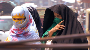 Two women with their faces covered walking in a crowded street