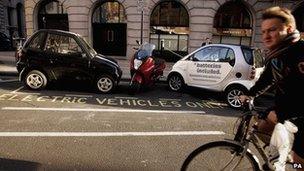 A man cycles past an electric car charging bay