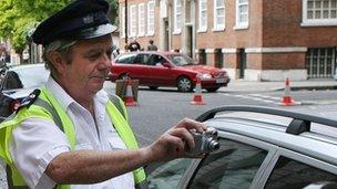 Traffic warden photographing car