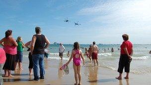 Black Cats perform as sea bathers look on