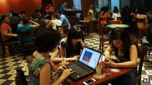 File photo: Three Vietnamese girls use a laptop and smart phones to go online at a cafe in Hanoi, Vietnam, on 14 May 2013