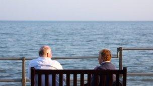 An elderly couple sits on a bench