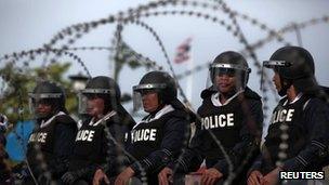 Thai riot policemen stand guard behind a barricade outside Government House in preparation for anti-government protests on 7 August 2013