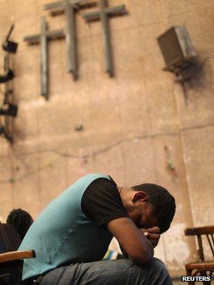 A Coptic Christian sleeps on a chair in a theatre inside Cairo's main Coptic cathedral, following clashes with Muslims (8 April 2013).