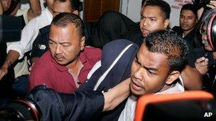 Former policemen Azilah Hadri, center covered with blue cloth, and Sirul Azhar Umar, back center covered with black cloth, are escorted by police as they leave a court in Shah Alam, outside Kuala Lumpur, Malaysia, on 9 April 2009