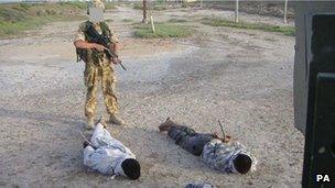 An unidentified British soldier stands over some of the detainees who have since given evidence to the inquiry