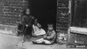 Children playing outside their slum home in London in 1910