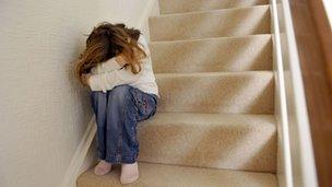 A young girl sits on a staircase with her head in her hands