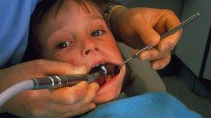 Child at dentist having tooth drilled to treat tooth decay