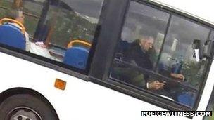 driver apparently using a mobile telephone while driving a bus