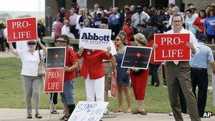 People hold signs protesting against State Sen Wendy Davis outside the venue hosting her rally on Thursday in Haltom City, Texas