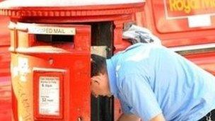 A postal worker collecting post in a mailbox