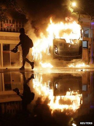 A man walks past a burning bus after demonstrators from the group Black Bloc set fire to it during a protest in Rio de Janeiro