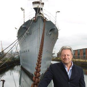 Nick Jellicoe stands in front of HMS Caroline