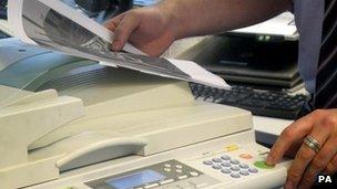 A worker uses a laser printer and photocopier in an office