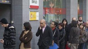 People queue outside a government unemployment office in Madrid, Spain