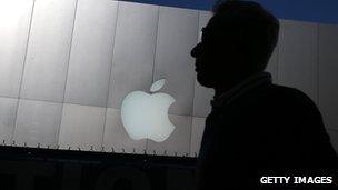 A man walking past an Apple logo