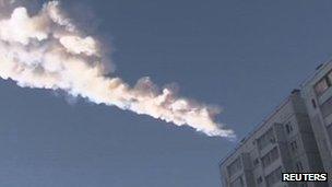 The trail of a falling object is seen above a residential apartment block in the Urals city of Chelyabinsk