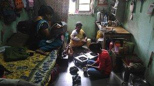 Women prepare lunch in a one-room home in Mumbai