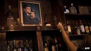 A bartender places a candle near a portrait of John F. Kennedy and Jacqueline Kennedy is seen in the Kennedy Room bar in Dallas 9 October 2013