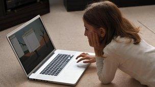 Young girl lying on carpet using laptop computer