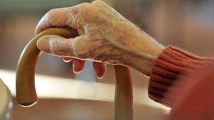 An elderly woman's hand on a stick