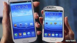 models hold a Samsung Galaxy S and a Galaxy S3 Mini (R) smartphones