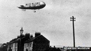 "Walter Willson's on top" slogan on side of airship over a North East town