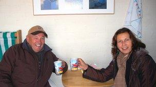 Roger and Sheila Widdup inside their hut with cups of tea