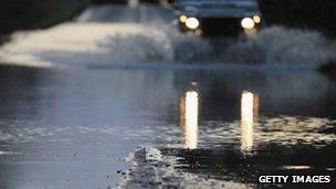 A car drives through a flooded road