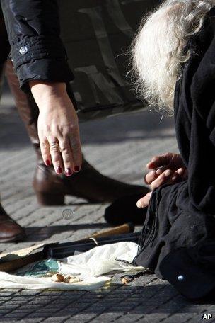 An elderly woman lies on the ground begging for alms in main street on the northern Greek port city of Thessaloniki in 2013