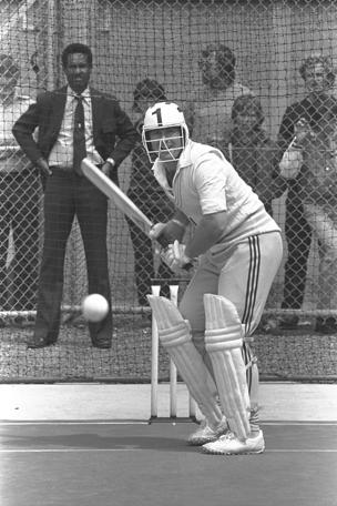 Dennis Amiss (with Garfield Sobers in background) modelling an early cricket helmet, 1978