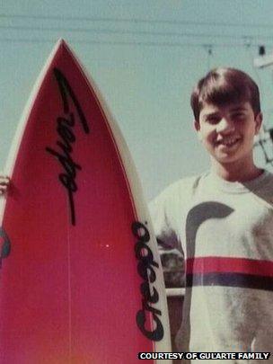 A young Gularte holding a surfboard