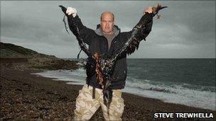 A man holding a dead gannet covered in oil PHOTO: Steve Trewhella