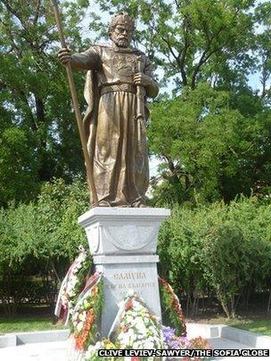 A daytime full-length shot of the statue with floral wreaths around the base