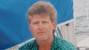 Farmer Thomas Olverson wearing a green shirt, sitting on a yacht on a body of water