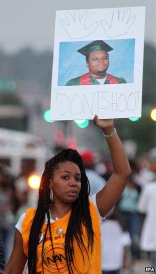 Demonstrators hold signs as protests continues after the shooting death of Michael Brown in Ferguson, Missouri, 17 August 2014