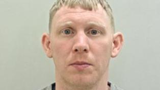 Police custody image of Ryan Gee who has blond hair and is wearing a grey top. 