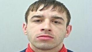 Police custody image of Terrence Kenny with brown hair and eyes wearing a red polo neck top and black jacket.