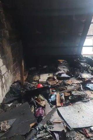 Piles of blackened objects and rubbish in an attic, with part of the roof exposed