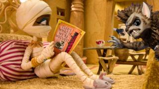Cleo from Scream Street reads a book as a werewolf comes through the door.