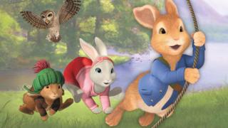 Peter Rabbit swinging on a vine with Lily and Benjamin hoping behind. An owl is flying over head.