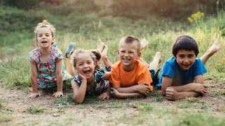 Four young children lying on the floor facing forward looking happy.
