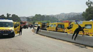 Emergency services near the scene of a coach crash in the Boumerdes region of Algeria. A variety of ambulances can be seen with emergency workers outside them.