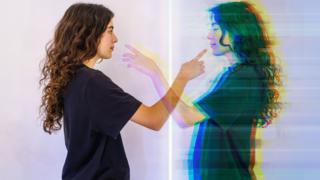 A woman looks at an image of herself