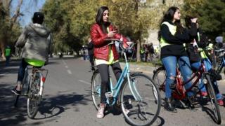 woman on bike on phone in Iraq