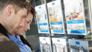 Young couple look at houses for sale in an estate agent's window