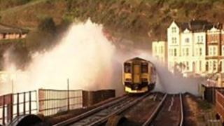 Railway track with a train as large wave breaks over the train