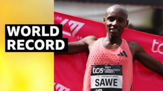 Sebastian Sawe holds up red flag behind his back after winning the 2026 London Marathon
